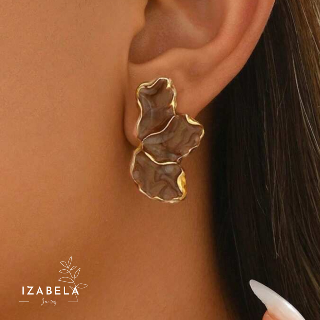 Gold leaf-shaped earring worn by a person with 'IZABELLA' branding.