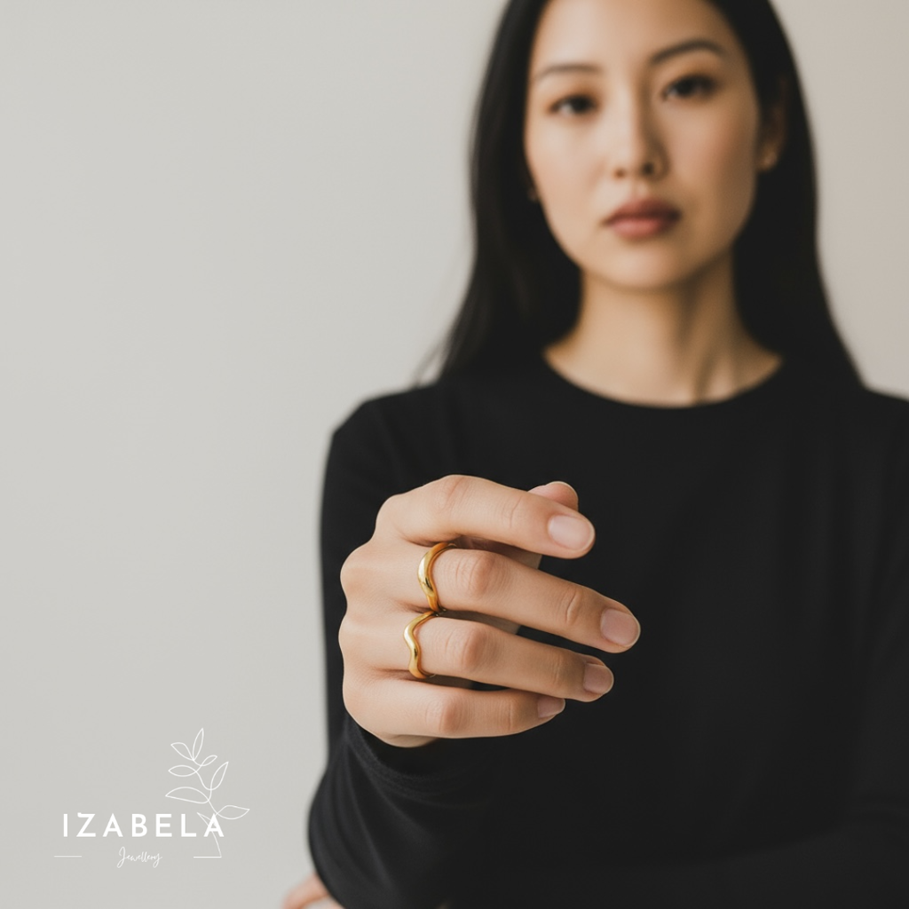 Woman wearing a gold ring with a plain background and 'Izabela' branding.