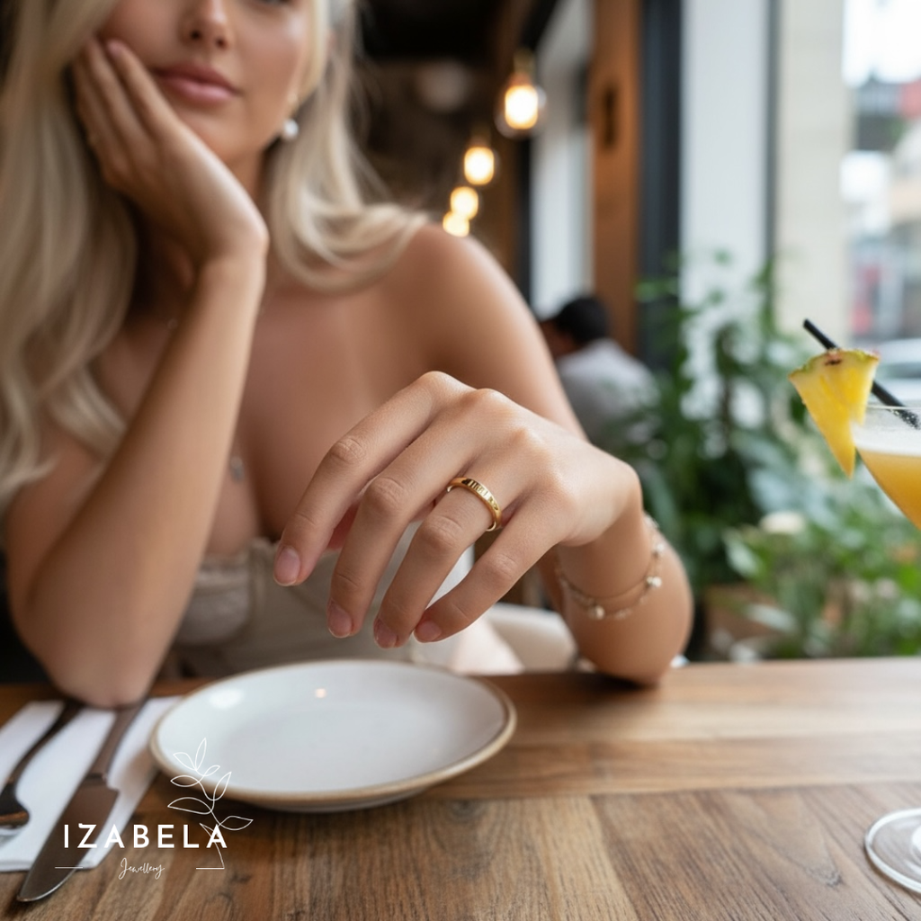 Woman sitting at a table with a plate and drinks, wearing jewelry.