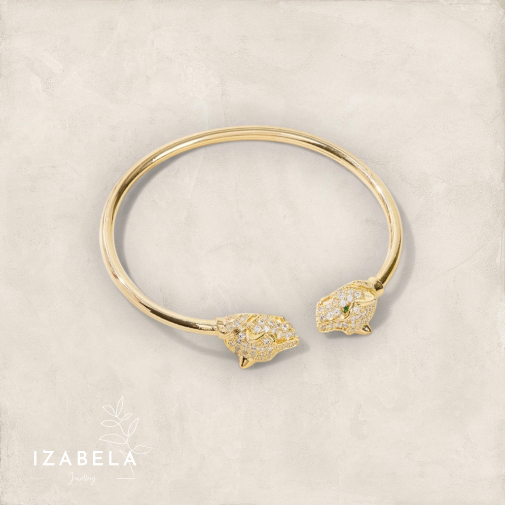 Gold bracelet with lion head ends on a beige background, featuring the brand 'Izabela'.