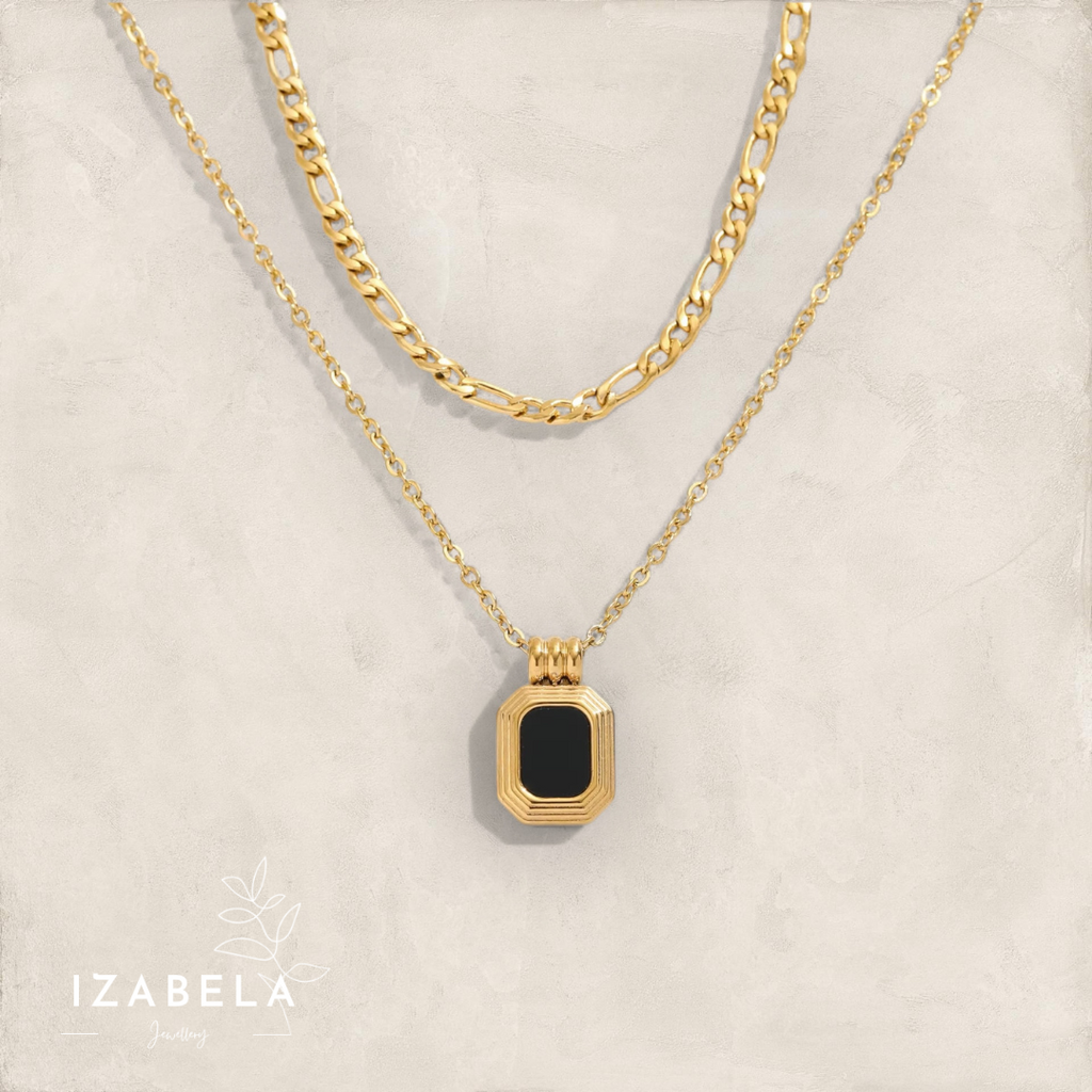 Gold necklace with a black pendant on a beige background, featuring the brand 'Izabela'.